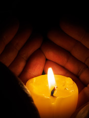 Hand around illuminated candle
