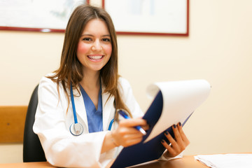 Smiling young doctor sitting in her office