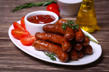 roasted sausages with tomato sauce and herbs on a wooden background