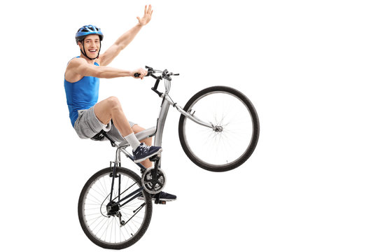 Confident young biker performing a wheelie