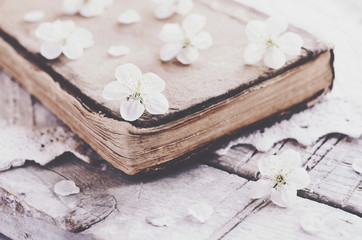 Cherry flowers laying upon old book on lace doily