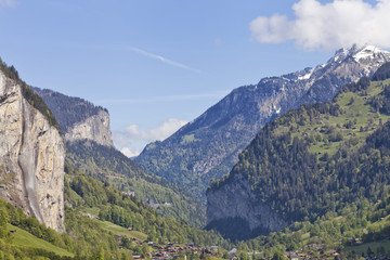 Lauterbrunnen valley in Swiss Alps, with snow mountain peaks, green alpine meadows, exposed rocks, high waterfalls