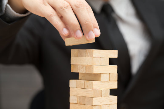 Businessman placing wooden block on a tower. Risk and strategy i