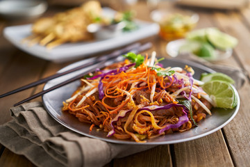 stir fried beef pad thai with color garnish and chopsticks