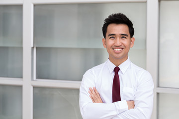 Asian businessman standing arms crossed and smiling