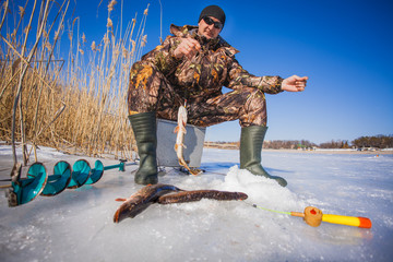 Fototapeta premium ice fisherman with pike caught on a tip up