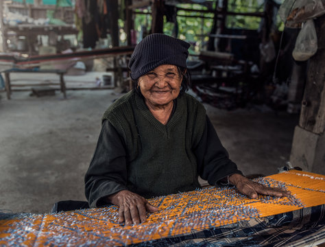 Old women demonstrate to procedure of making Thai Silk weaving