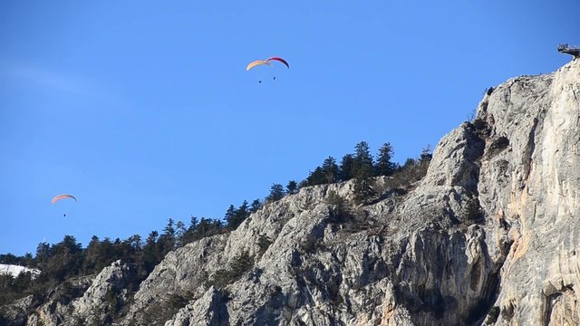 drei paragleiter bei hoher felswand