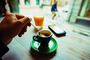 Close up on the hand of man stirring the coffee in a cup - break