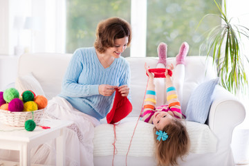 Mother and daughter knitting woolen scarf