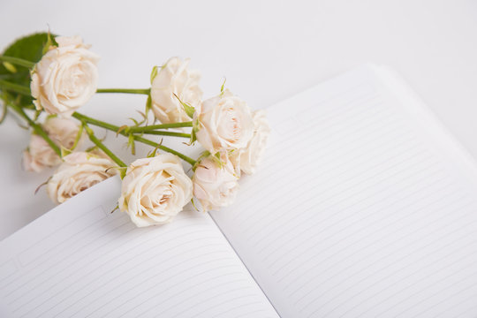 Bouquet of creamy roses lying on open notebook