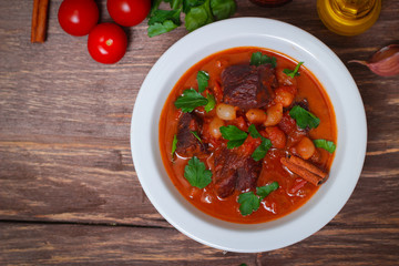National Greek dish stifado with beef, tomatoes and onions, stewed in red wine with Herbs on a wooden background, horizontal