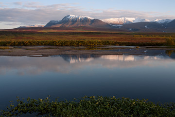 Reflection of snow-covered mountains in a tranquil river. Polar Urals. Russia.