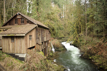 Old wooden mill next to a scenic creek
