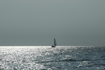 Obraz premium Lonely sailing boat. Seascape with the silhouette of sailing ship in dramatic light.