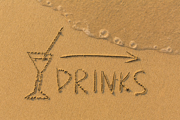 Inscription Drinks and the arrow drawn on the beach sand with a soft transparent waves.