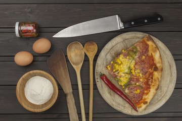 Homemade pizza. Portions of pizza on a dark wooden table. Food preparation.
