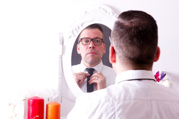 Mann bindet sich vor Spiegel die Krawatte