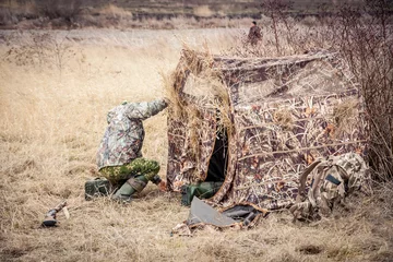 Crédence de cuisine en verre imprimé Chasser Homme installant la tente de chasse dans le domaine rural