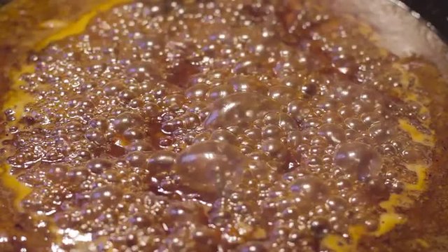 Close up of sauce caramelizing and bubbling in cast iron skillet