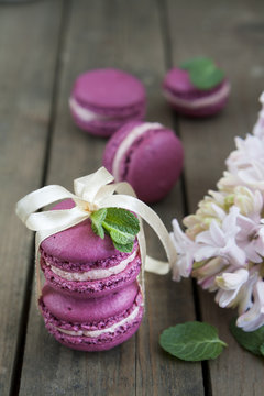 Sweet crimson french macaroons tied with ribbon with hyacinth and mint on dark wooden background