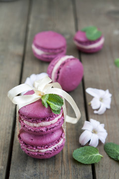 Sweet crimson french macaroons tied with ribbon wiht hyacinth flowers and mint on dark wooden background