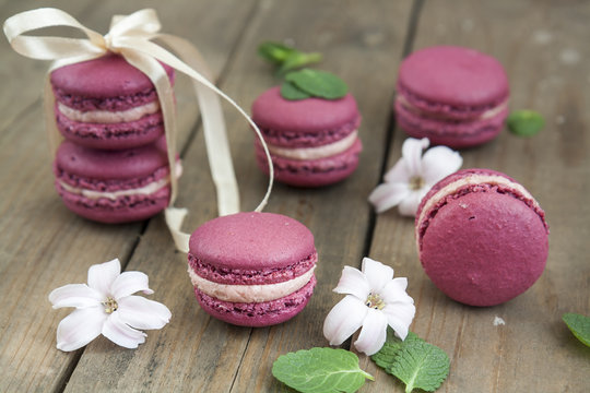Sweet crimson french macaroons  wiht hyacinth flowers and mint on dark wooden background
