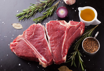 Raw fresh meat t-bone steak with spices, garlic and rosemary