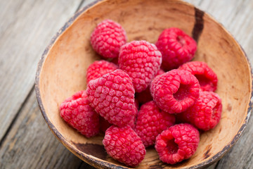 Frozen raspberries on wooden background.