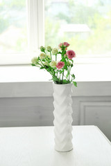 Beautiful spring flowers in vase on window background