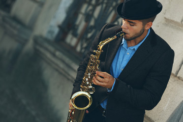 Naklejka premium Man with saxophone outside near the brick wall