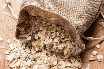 oat flakes cereal in burlap sack on wooden table.