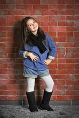 Portrait of little fashion kid girl on bricks wall background