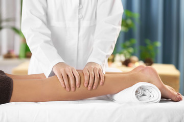 Beautiful young woman relaxing with leg massage at beauty spa