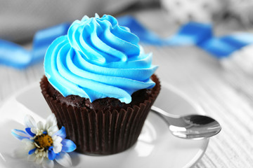 Delicious chocolate cupcake with blue cream on decorated wooden  table, close up