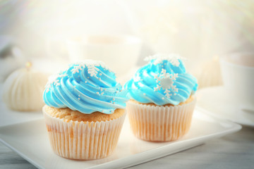 Two tasty blue cupcakes with decorations on light background