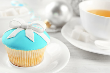 Tasty blue cupcake on plate with decorations, closeup