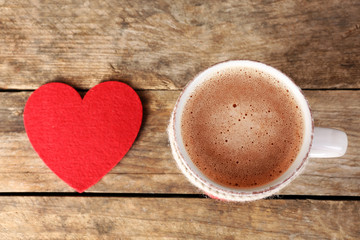 Cup of coffee with red felt hearts on wooden background, close up