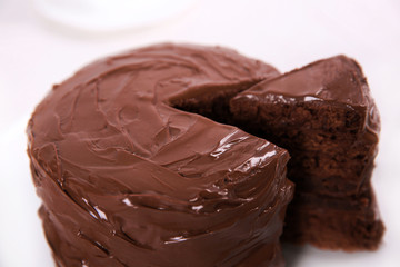 Chocolate cake on plate with a cut piece on unfocused background, closeup