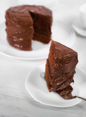 Chocolate cake on plates with a cut piece on unfocused background
