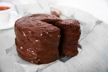 Chocolate cake with a cut piece on wooden table background, closeup