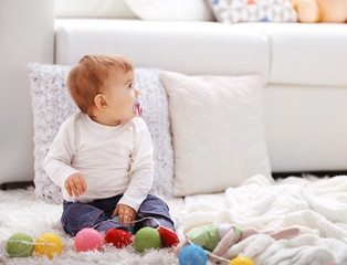 Sweet baby girl with a soother playing on a floor