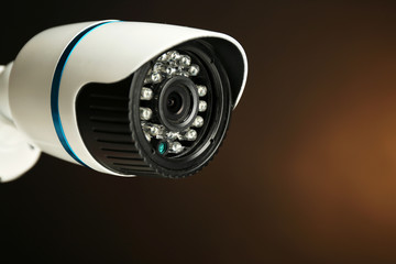 Security CCTV camera on dark yellow background, closeup