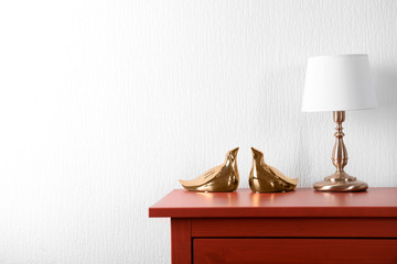 Room interior with red wooden commode and lamp on light wall background