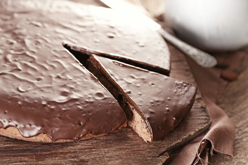 Sliced chocolate frosting cake on wooden table