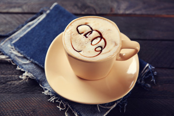 Milk coffee in glass cup with chocolate syrup on black wooden table