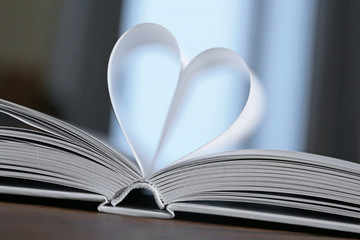 Heart from book pages on dark blurred background