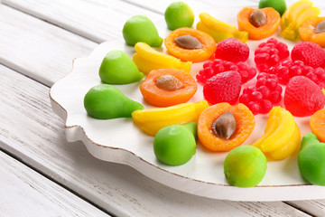 Fruit candies on mat on wooden background
