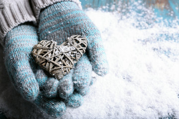 Fototapeta na wymiar Female hands in mittens with heart on snow background