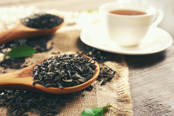 Still life with granulated tea and green leaves on wooden table closeup